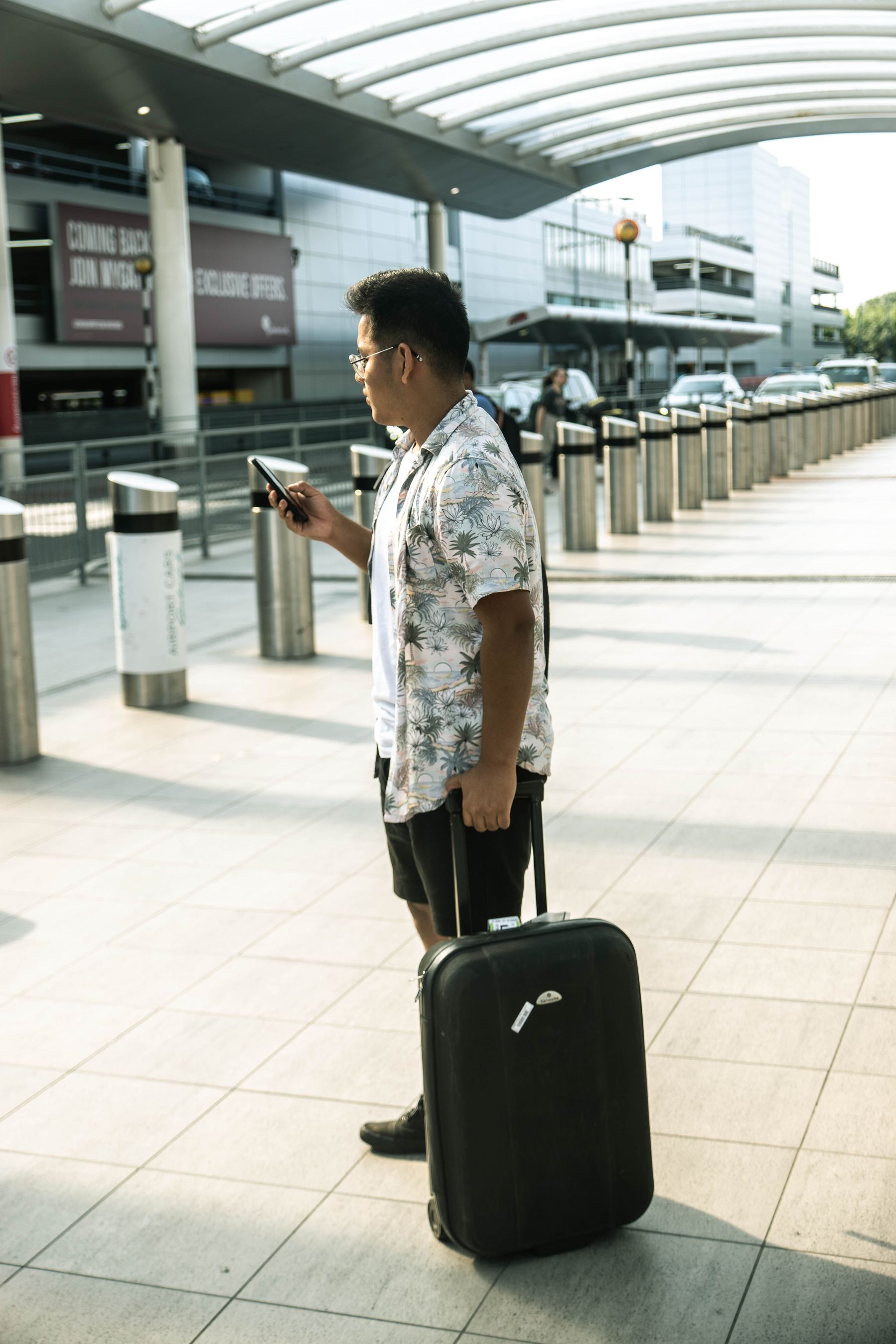 man at airport with luggage looking at phone