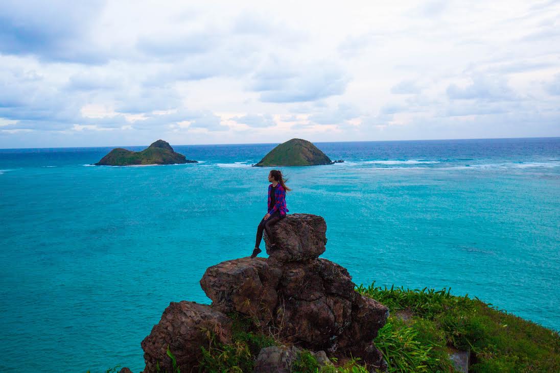 Mujer sentada en las rocas mirando el mar