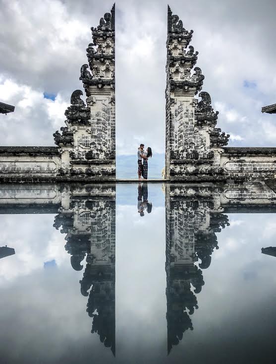 couple on vacation standing together at a statue overlooking the ocean