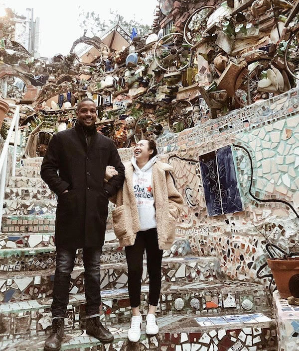 couple standing on stairs in front of tile walkway and artwork