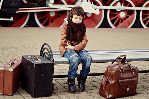 kid sitting on bench with suitcases waiting for self transfer flight