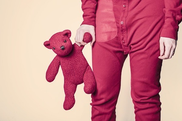 person in red pajamas holding a red teddy bear